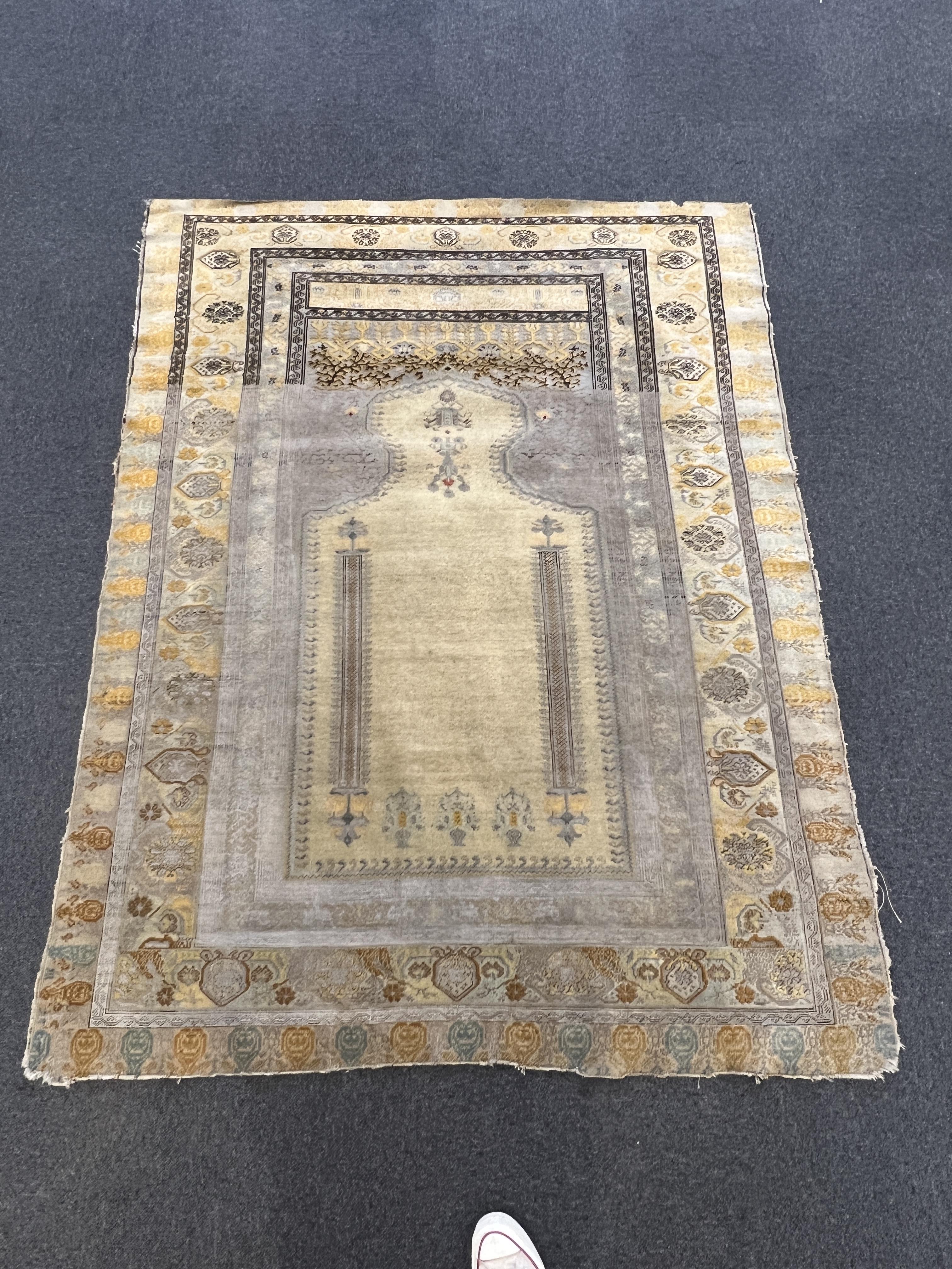 A Turkish silk prayer rug, with mihrab and stylised foliate borders on a gold ground, 185 x 137cm. Condition - the central panel severely worn to the tip of the mirror, lower fringe worn with losses.
